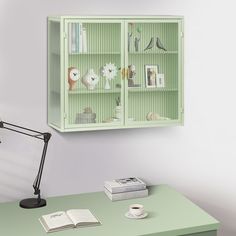 a green bookcase with books on it next to a desk lamp and other items