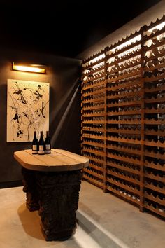 a wine cellar with several bottles on the table and an art piece hanging above it