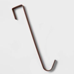 a metal hook on the side of a white wall with a brown handle and long end