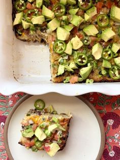 a white plate topped with a slice of cake covered in avocado and other toppings