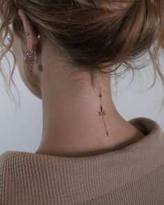 a woman's neck with a small flower tattoo on the back of her neck