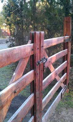 an old wooden gate is open to reveal the grass and trees in the back ground