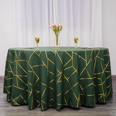 two vases with flowers sit on top of a green table cloth that has gold lines