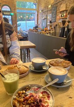 two women sitting at a table with plates of food and drinks in front of them