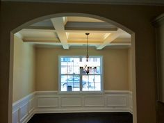 an empty room with wood flooring and white trim on the walls is seen through an archway