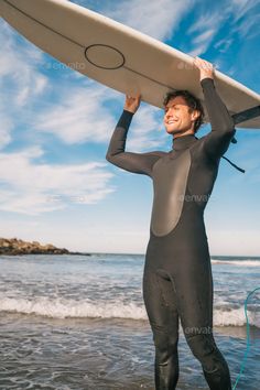 a man in a wet suit holding a surfboard on the beach - stock photo - images