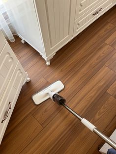 a person using a mop to clean the floor in a room with white cabinets