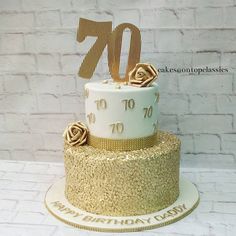 a white and gold birthday cake with roses on top