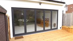 a patio with wooden flooring and sliding glass doors on the side of a house