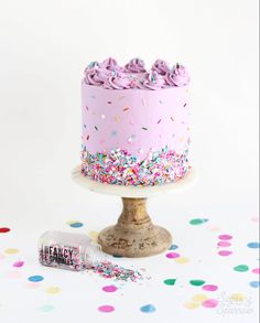 a pink cake with sprinkles on it and a candy bar next to it