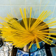 yellow noodles are being cooked in a pot on the stove top with tin foil around them