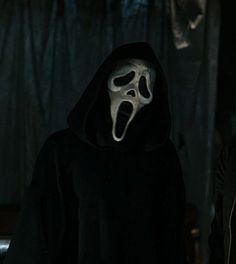 two people wearing masks in the dark, one with a ghost mask on his face