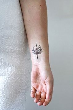 a woman's hand with a small tattoo on her left wrist and the word, lotus