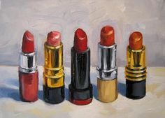 three red lipsticks are lined up on a white surface, and one is in the foreground