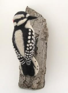 a stuffed bird sitting on top of a piece of wood next to a white wall