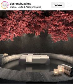 a bed sitting in the middle of a room next to a tree with red leaves