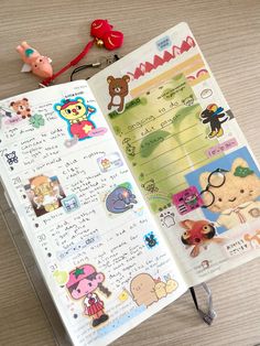 an open notebook with stickers on it sitting next to a toy bear and keychain