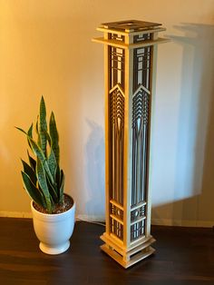 a tall wooden tower next to a potted plant on top of a hard wood floor