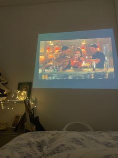 two people sitting at a table in front of a projector screen with food on it