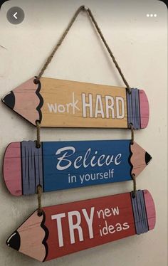 three wooden pencils hanging on a wall with the words work hard, believe in yourself and try ideas