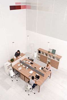 an overhead view of two people working at desks in the middle of a room