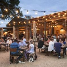 people are sitting at tables outside in the evening