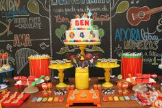 a birthday cake and decorations on a table with chalkboard in the backround