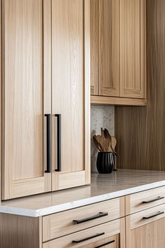 a kitchen with wooden cabinets and white counter tops, including a black vase on the island