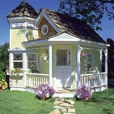 a small yellow house sitting on top of a lush green field