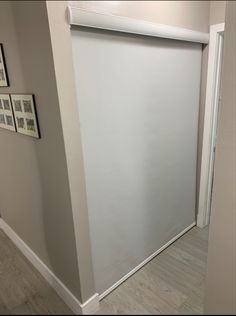 an empty room with pictures on the wall and a white roller up door in front of it