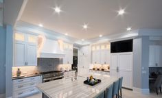 a large kitchen with white cabinets and marble counter tops