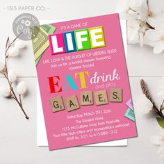 a pink card with the words eat drink and games on it next to some flowers