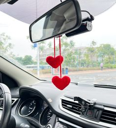 two red hearts hanging from the dashboard of a car