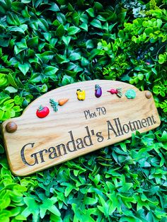 a wooden sign that says grandad's alotment surrounded by green bushes