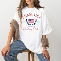 This USA Drinking Team Shirt is perfect for your next summer party for Memorial Day or 4th of July. Watch the Summer Games cheering on America in your new drinking shirt.  Comfort Colors introduces its garment-dyed t-shirt; a tee made 100% with ring-spun cotton. The soft-washed, garment-dyed fabric brings extra coziness to your wardrobe while the relaxed fit makes it an excellent daily choice. The double-needle stitching throughout the tee makes it highly durable while the lack of side-seams hel Summer Team Spirit T-shirt, White Team Spirit T-shirt For Summer, Summer Team Spirit Top With Graphic Print, Summer Tops With Graphic Print For Team Spirit, Summer Team Spirit Crew Neck T-shirt, Summer Team Spirit T-shirt With Graphic Print, Summer Team Spirit Screen Print Top, Summer Cotton T-shirt With Team Spirit Style, Summer Cotton T-shirt With Team Spirit