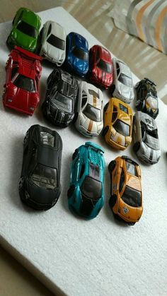 a bunch of toy cars sitting on top of a white table next to each other