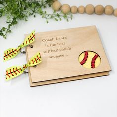 a wooden plaque with a softball on it next to a plant and some string beads