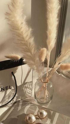 a pair of earrings sitting on top of a table next to a vase filled with feathers