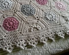 a crocheted blanket on top of a bed covered in pink and white circles