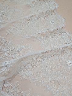 three pieces of white lace sitting on top of a tablecloth covered in flowers and leaves