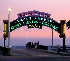 the entrance to santa monica yacht harbor is lit up with neon signs and palm trees