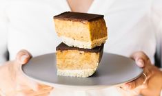 two pieces of cake on a plate being held by a woman in white shirt and jeans