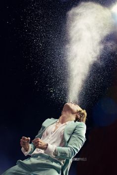 a woman in a blue suit blowing white powder into the air