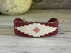 a red and white beaded bracelet sitting on top of a wooden table