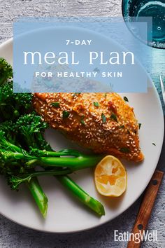 a white plate topped with broccoli and fish next to a glass of water