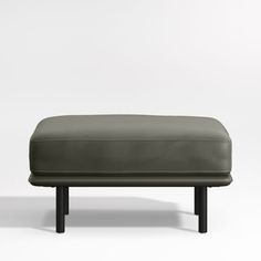 a grey leather ottoman sitting on top of a white floor