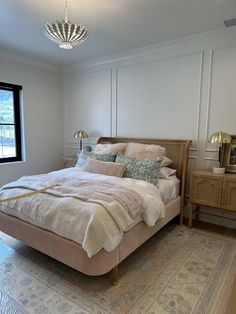 a bedroom with a bed, nightstands and a window in the corner that has a chandelier hanging above it