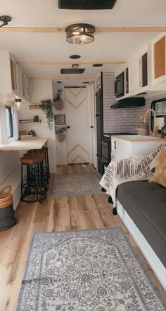 the interior of a tiny home with wood floors and white walls, an area rug, and black appliances