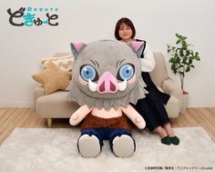 a woman sitting on top of a couch next to a large stuffed animal with blue eyes