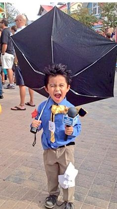 a young boy is holding an umbrella in the middle of his head and it looks like he's having fun